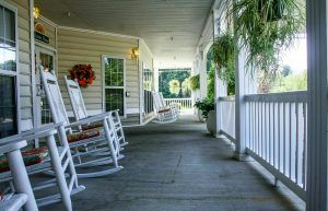 A cozy porch with rocking chairs and hanging plants, perfect for relaxation.