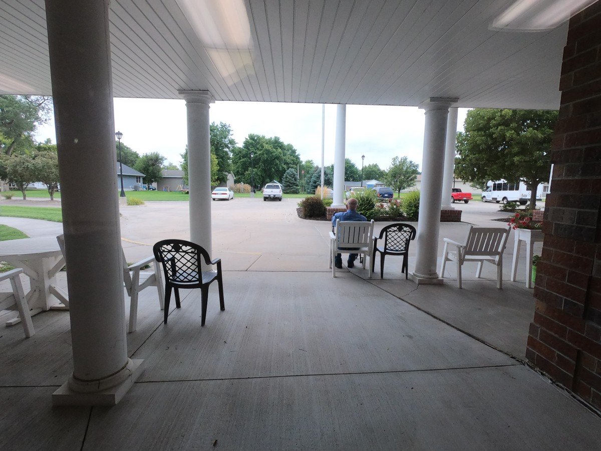 View from a covered patio area facing the parking lot with chairs and columns.