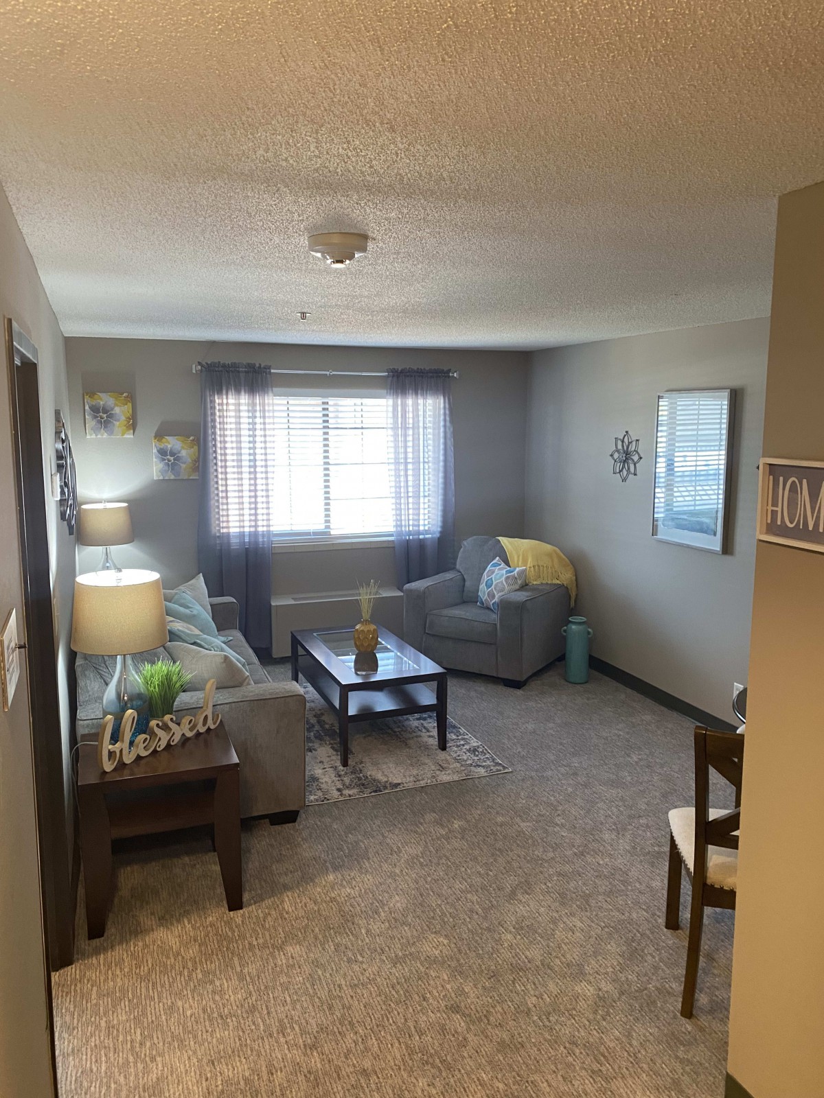 A cozy living room with a sofa, coffee table, and ample natural light.