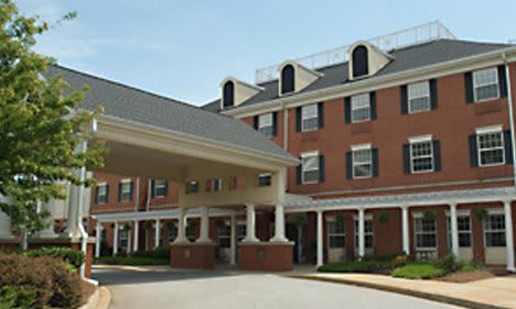 A front view of a brick building with a covered entrance and white columns.