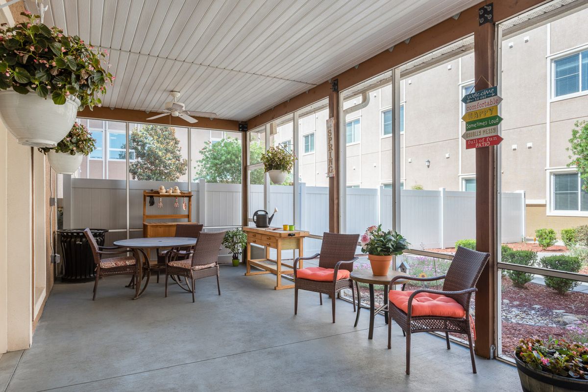 A cozy covered porch with outdoor seating and plants.