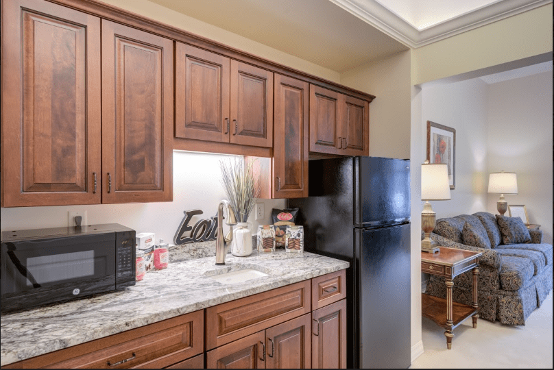 A modern kitchen with wooden cabinets, granite countertops, and various appliances.