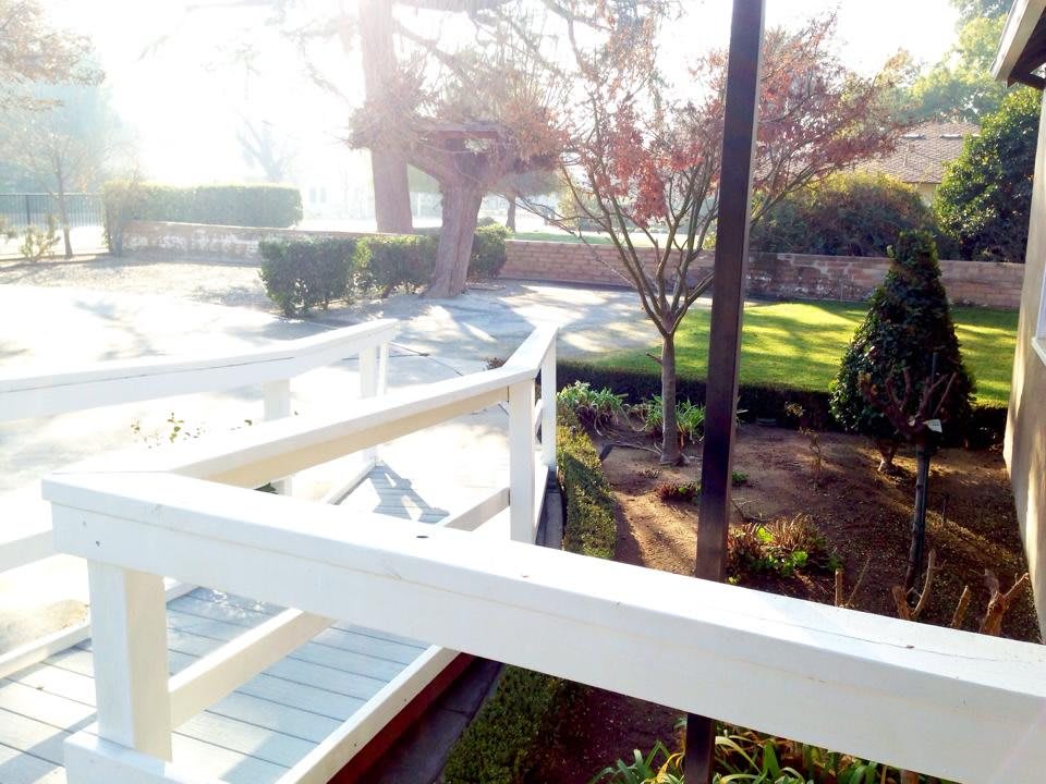 A serene garden view with a white bridge and trees bathed in sunlight.