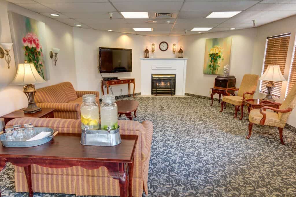 A cozy living room with a fireplace and seating area, featuring a television and decorative elements.