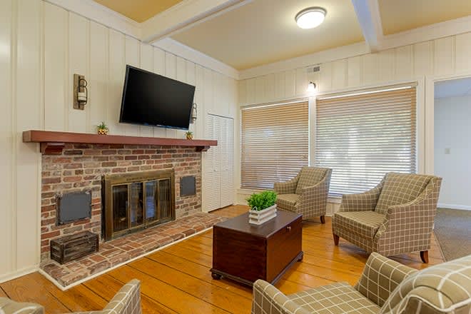 A cozy living room with a brick fireplace, television, and comfortable seating.