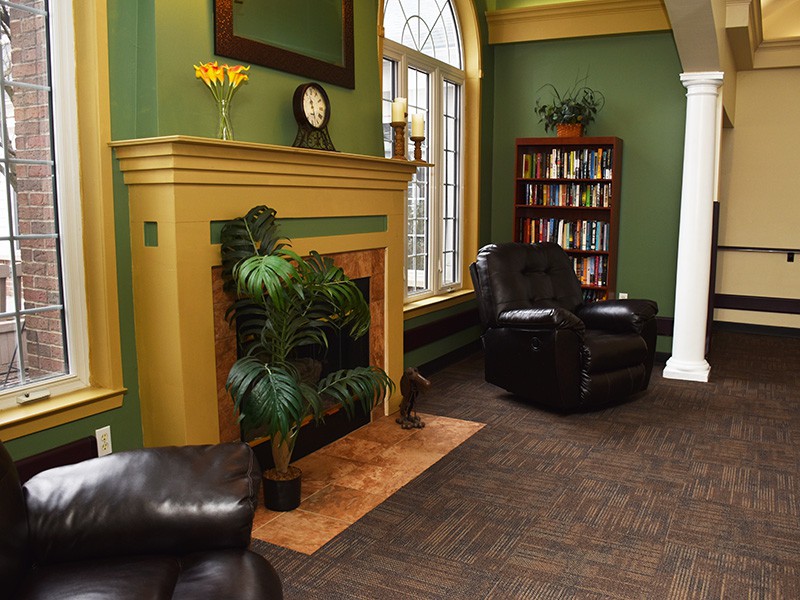 Cozy living room with green walls, a fireplace, and leather chairs.