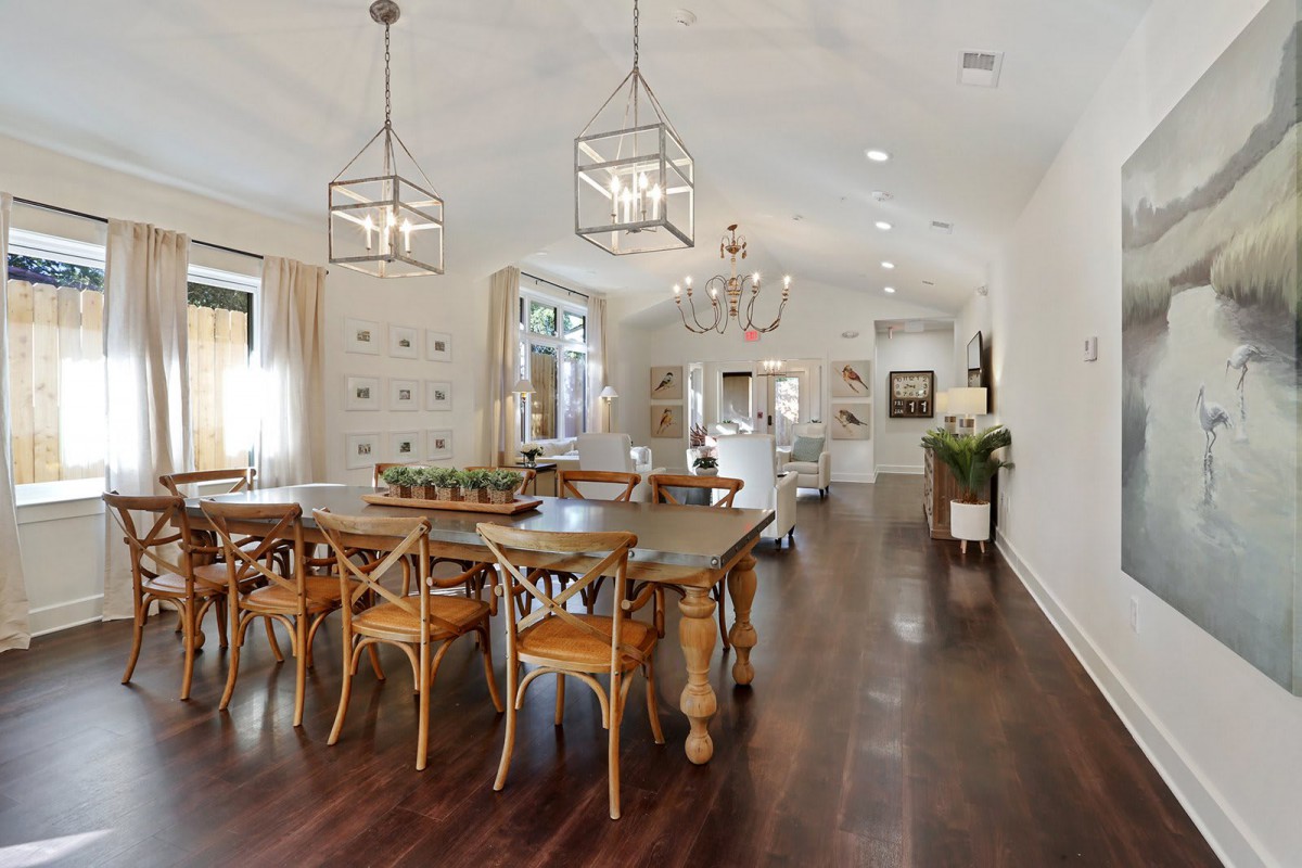 A modern and spacious dining room with elegant chandeliers and wooden flooring.