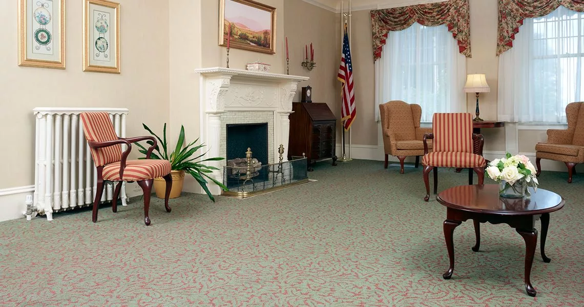 A traditional living room with a fireplace, American flag, and classic furniture.