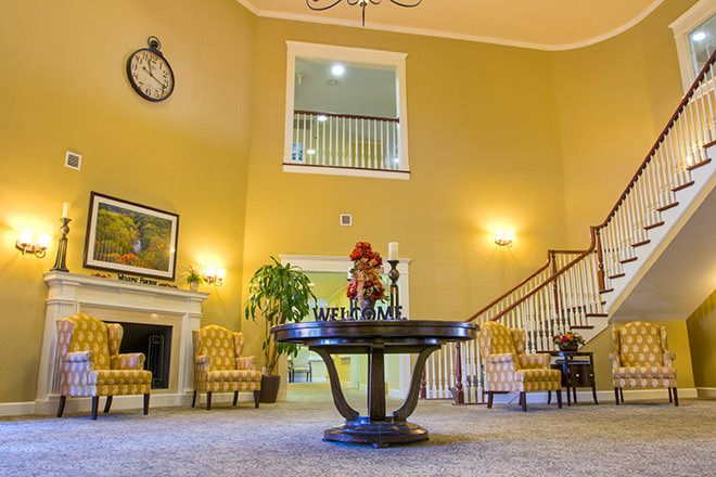 A spacious lobby with elegant decor, featuring a central table and a staircase.