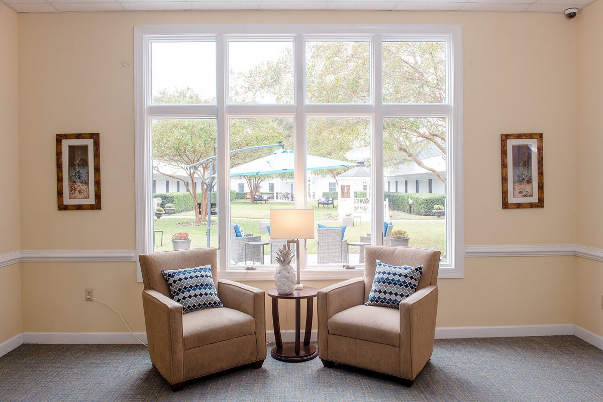 A cozy living room setup with two armchairs and a lamp by a large window.