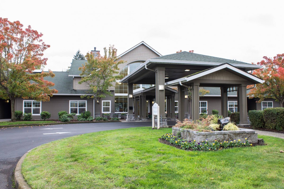 A well-maintained building entrance with landscaped lawns and trees.