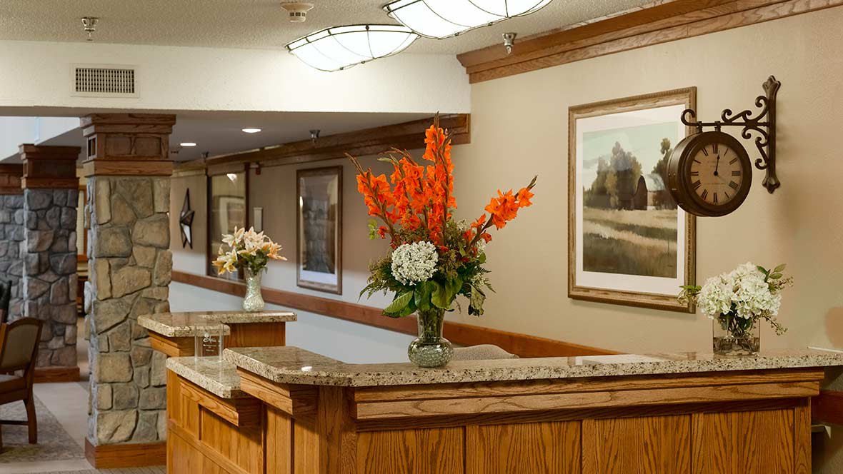 A cozy hotel lobby with a reception desk adorned by vibrant floral arrangements and framed artwork on the walls.