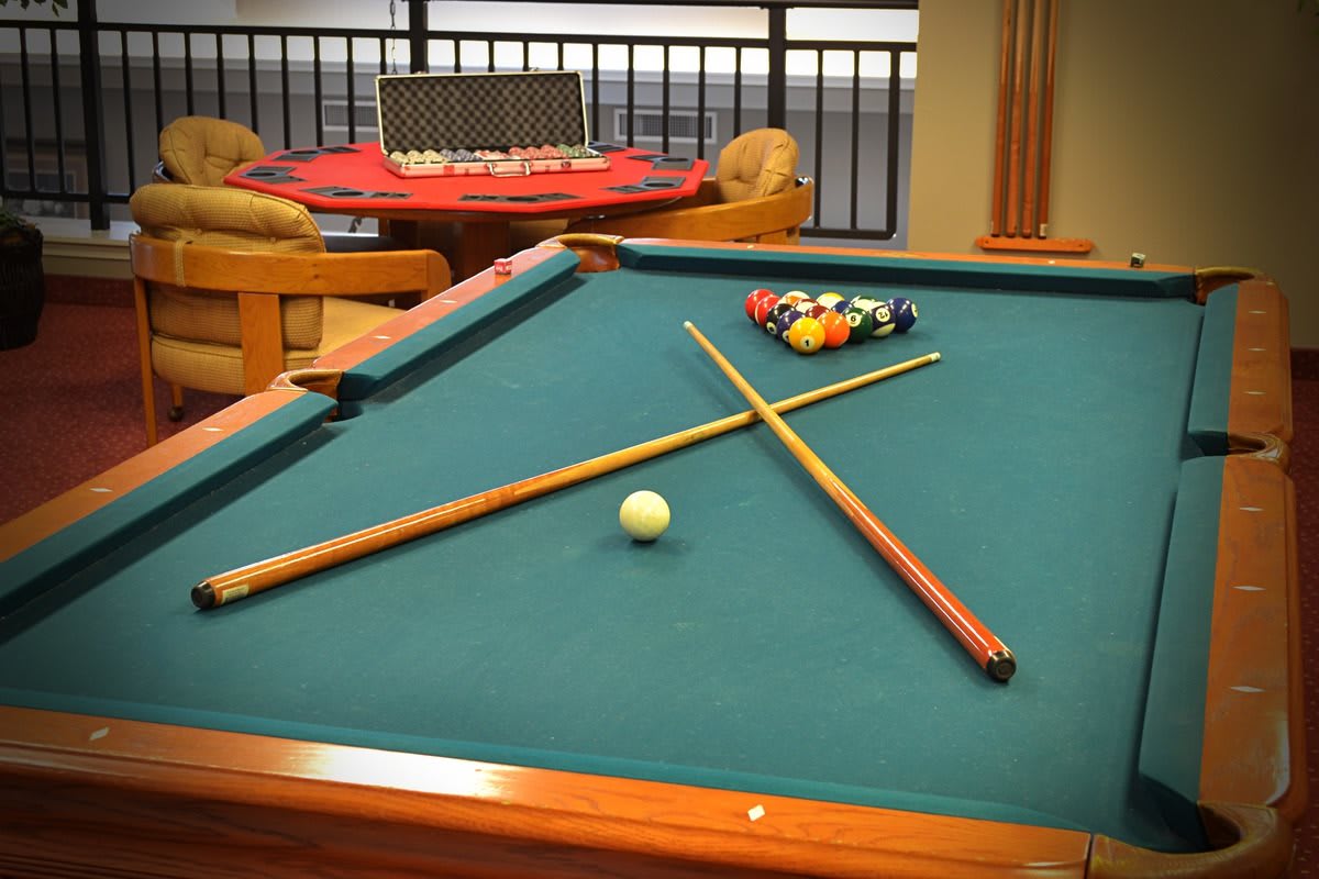 A billiards table set for a game with cue sticks and balls in a cozy game room.