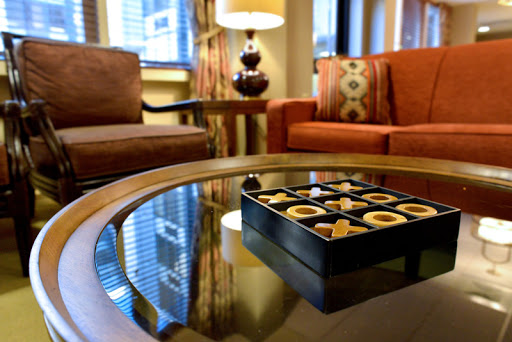 A cozy hotel lounge featuring comfortable seating and a box of assorted chocolates on the table.