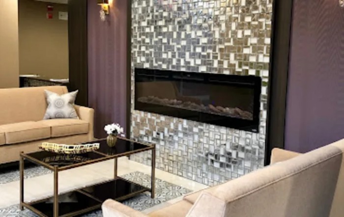 A modern living room with a sleek fireplace and mosaic tile wall.