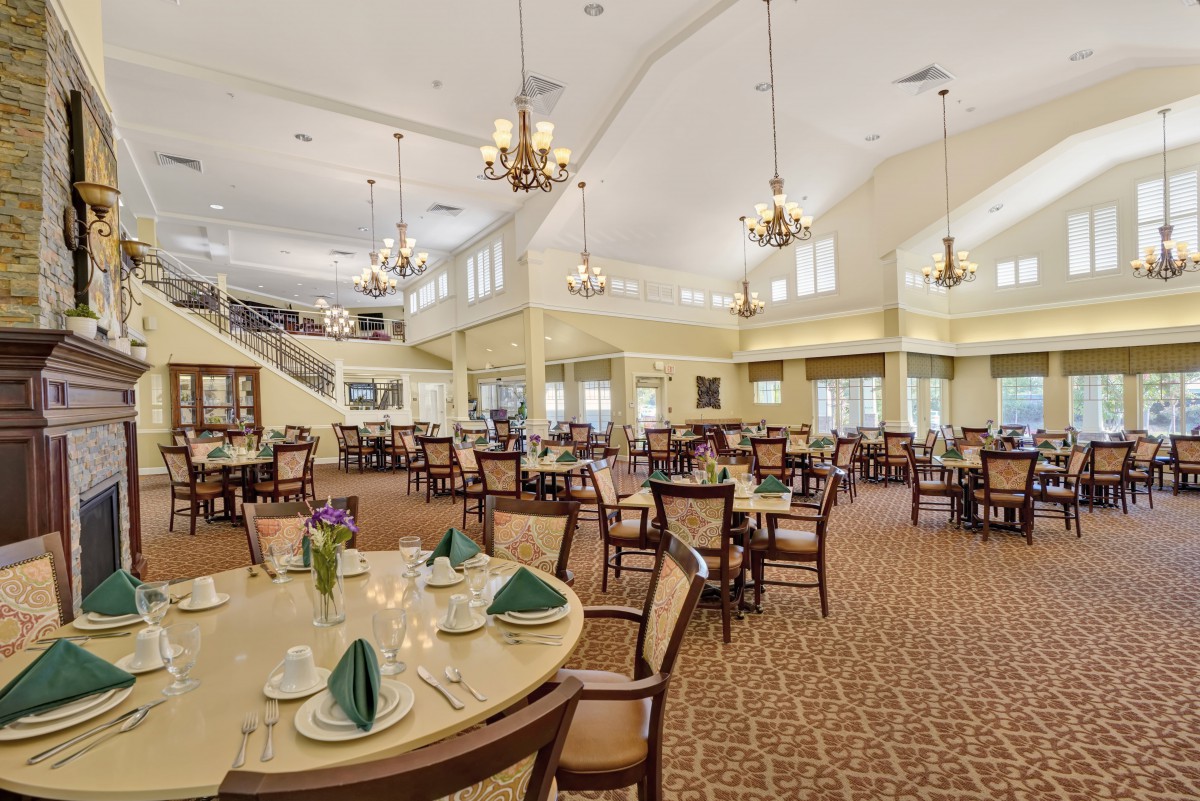 A spacious restaurant dining area with elegantly set tables and chandeliers.