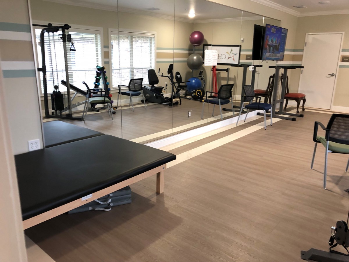 A well-equipped gym with various exercise machines and a mirrored wall.
