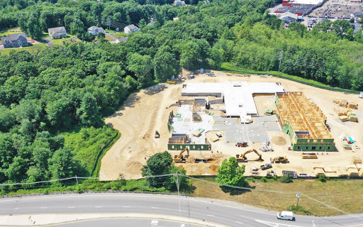 An aerial view of a construction site surrounded by greenery, showcasing ongoing land development.