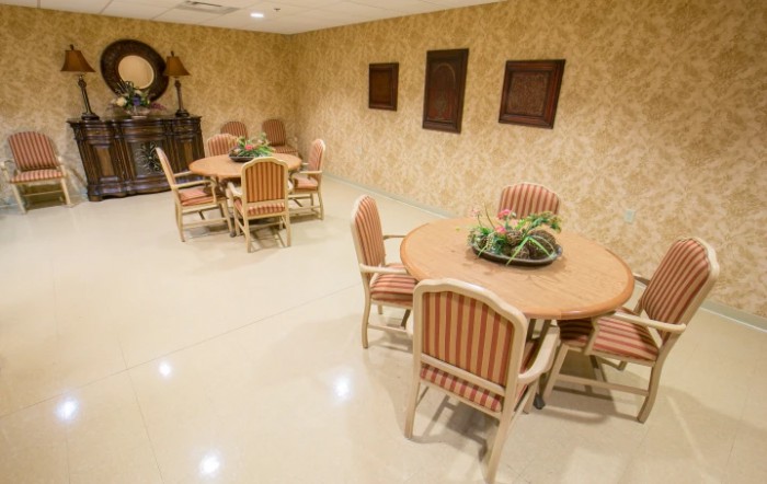 A cozy dining area with round tables and chairs, decorated with plants and wall art.