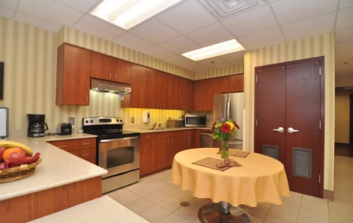 A modern kitchen with stainless steel appliances and a small round table decorated with flowers.