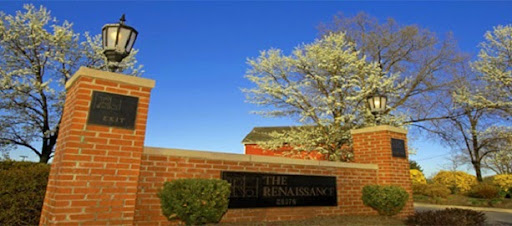A scenic view showing a sign for The Renaissance, surrounded by greenery and a clear blue sky.