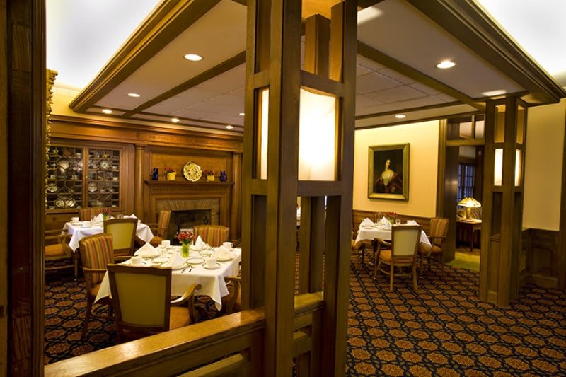 A warmly lit restaurant interior with elegantly set tables and comfortable seating.