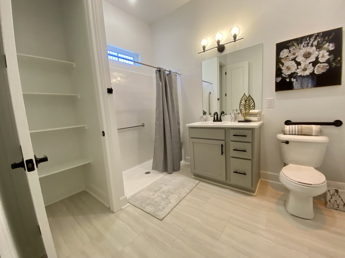 A modern bathroom featuring a spacious shower, sleek sink area, and convenient storage.