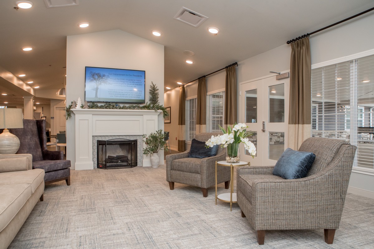 A modern living room featuring a fireplace, comfortable seating, and a large television.