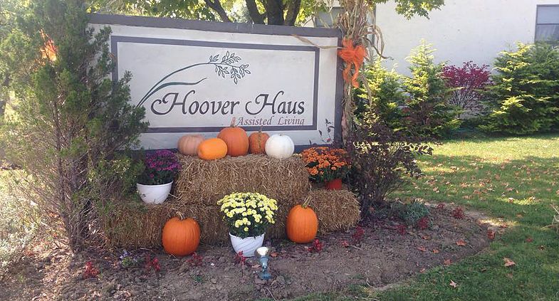 An autumn display featuring pumpkins and flowers in front of the Hoover Haus sign.
