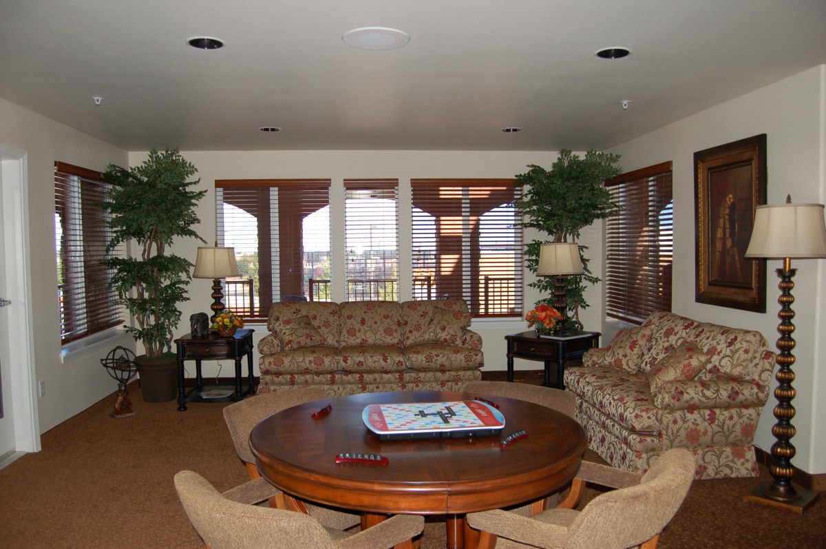 A cozy living room with large windows, comfortable seating, and decorative plants.