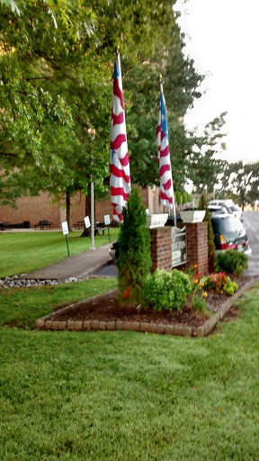 A well-maintained garden area featuring American flags in front of a building.