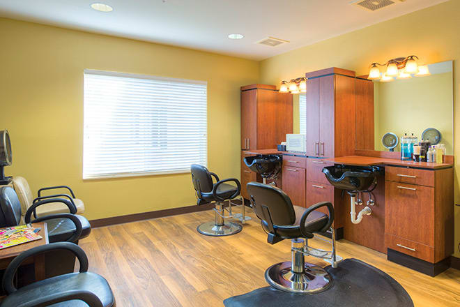 Interior of an empty hair salon with chairs, mirrors, and wooden flooring.