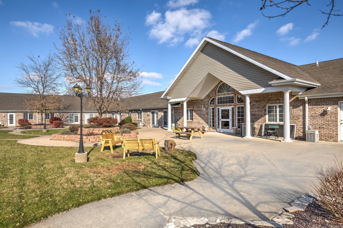 A well-maintained building with an outdoor seating area and garden under a clear blue sky.