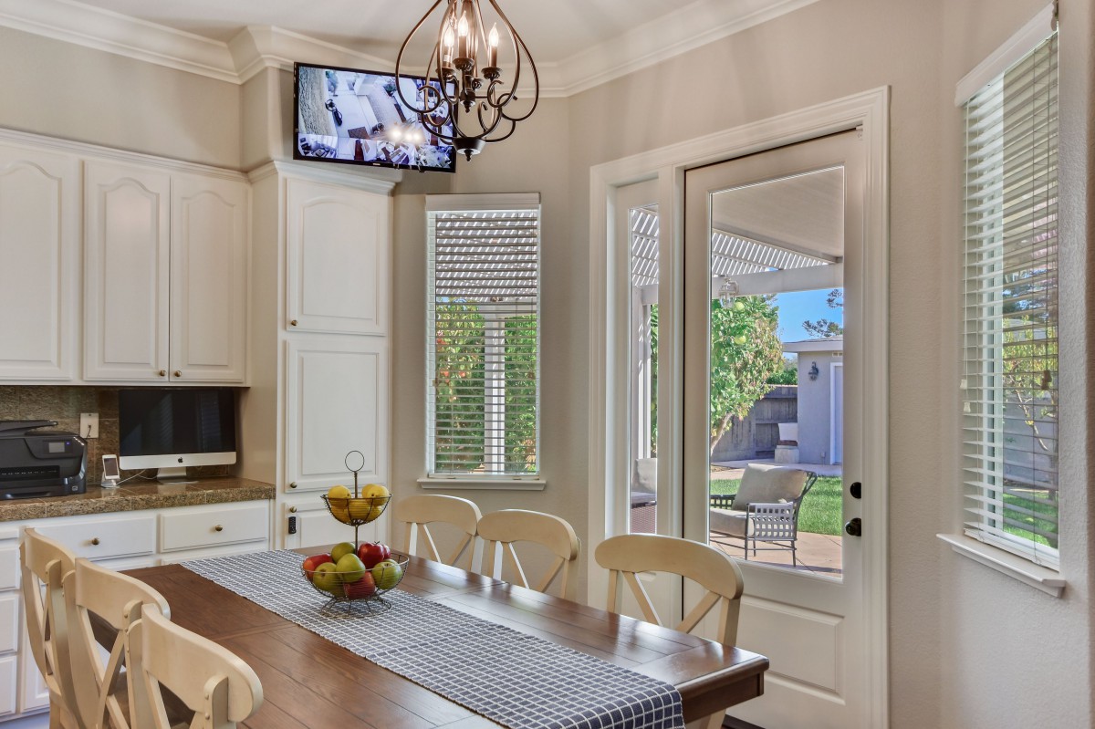 A cozy kitchen-dining area with a wooden dining table, overhead chandelier, and wall-mounted television.