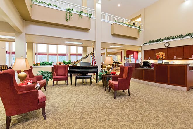 A spacious lobby area with a grand piano, surrounded by comfortable red chairs and tasteful decor.