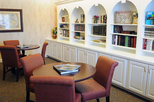 A cozy study area featuring round tables, comfortable seating, and illuminated bookshelves.