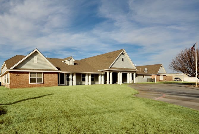 A suburban house with a large lawn under a partly cloudy sky.