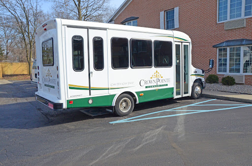 A white and green bus parked in a lot, ready for passengers.
