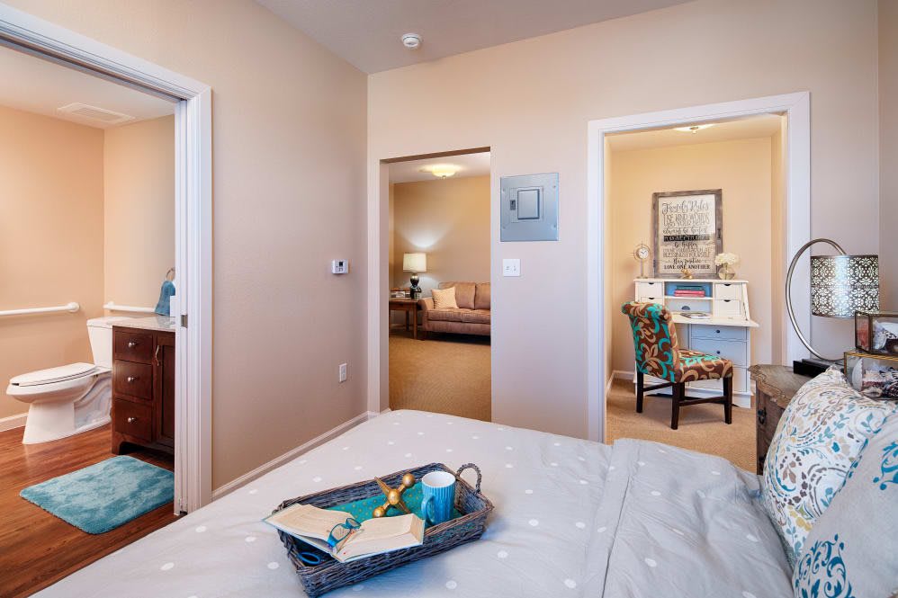 A cozy bedroom with a tray on the bed and view into adjoining rooms.