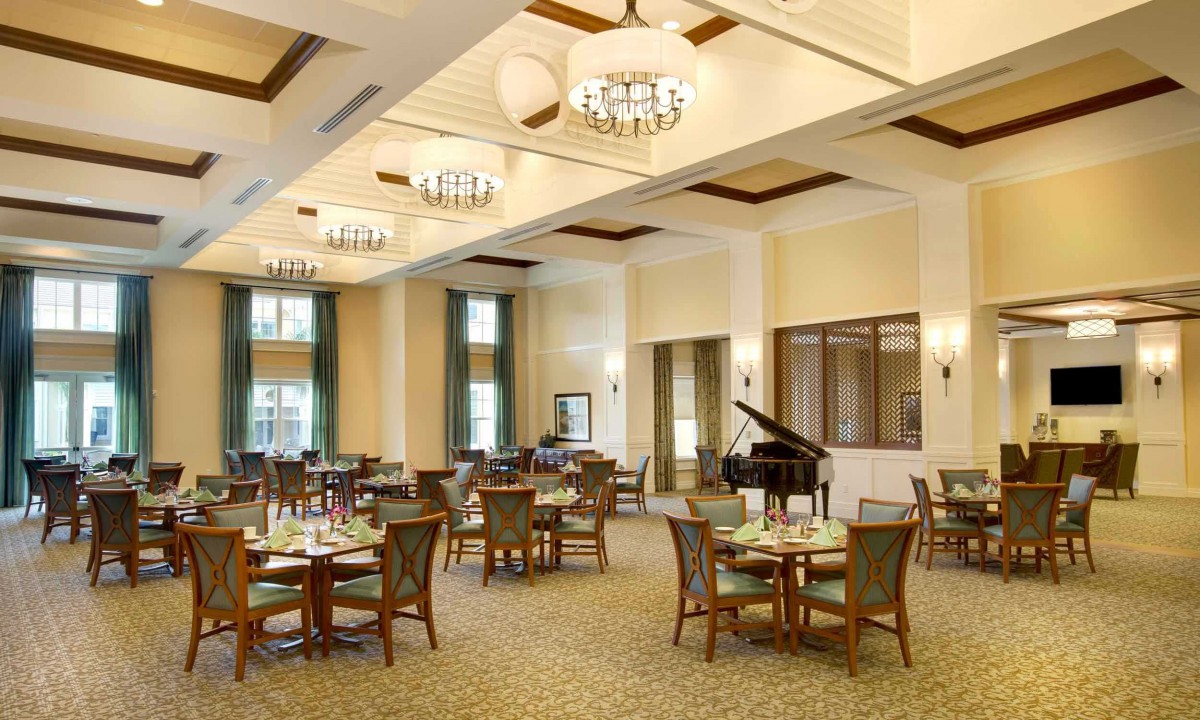 A spacious dining hall with elegant tables and chairs, featuring a piano and stylish lighting.
