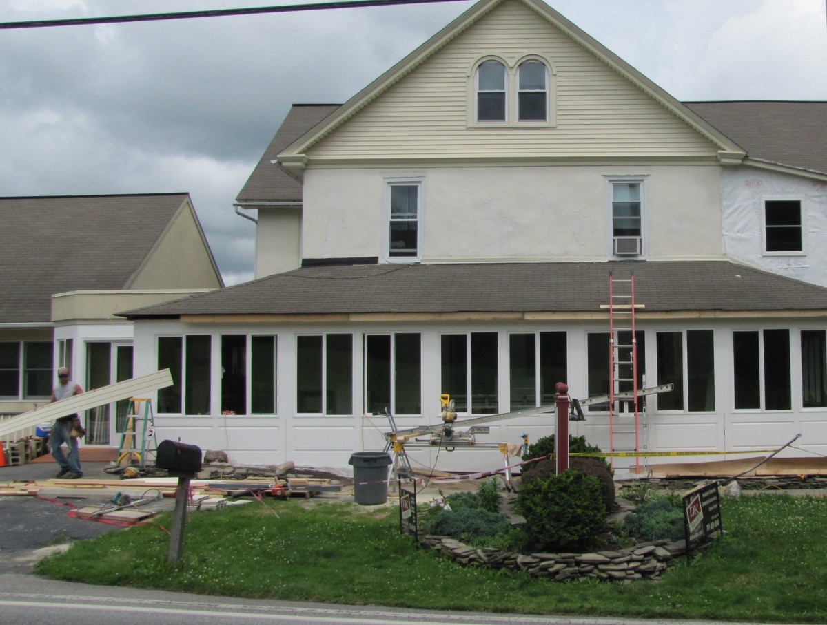 A house undergoing renovation with new windows and construction materials in the yard.