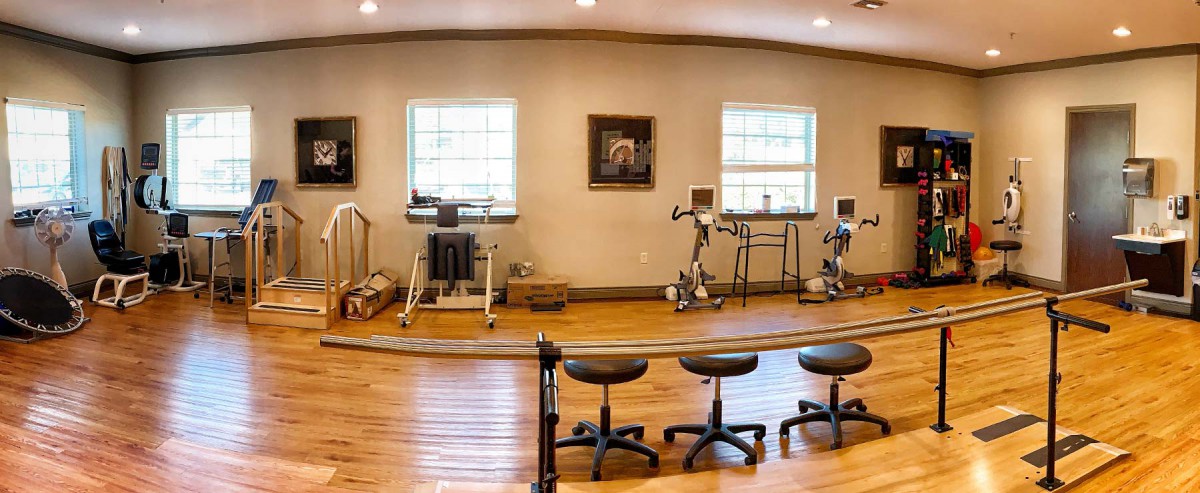 A rehabilitation room equipped with exercise machines and seating for physical therapy sessions.
