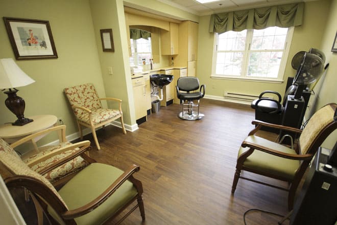 A cozy salon with several chairs and a hair styling station next to large windows.