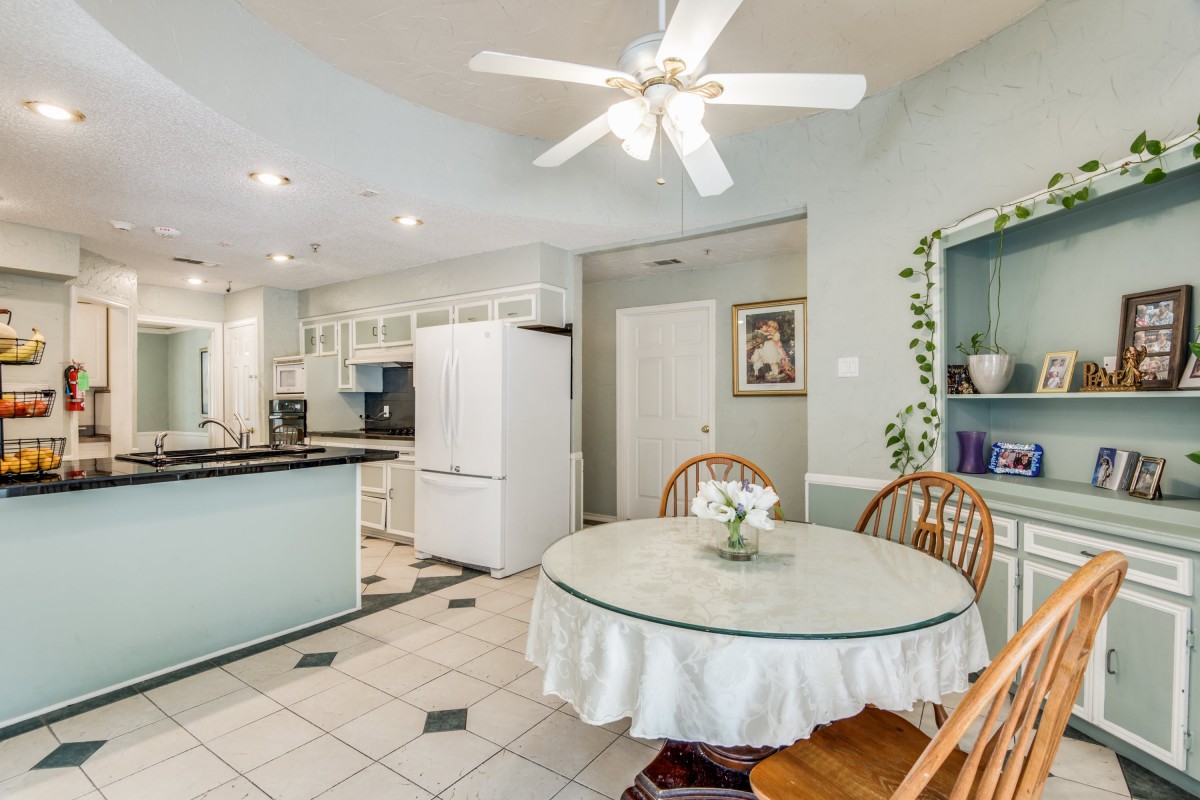 A cozy kitchen and dining area with a round table, wooden chairs, and white cabinets.