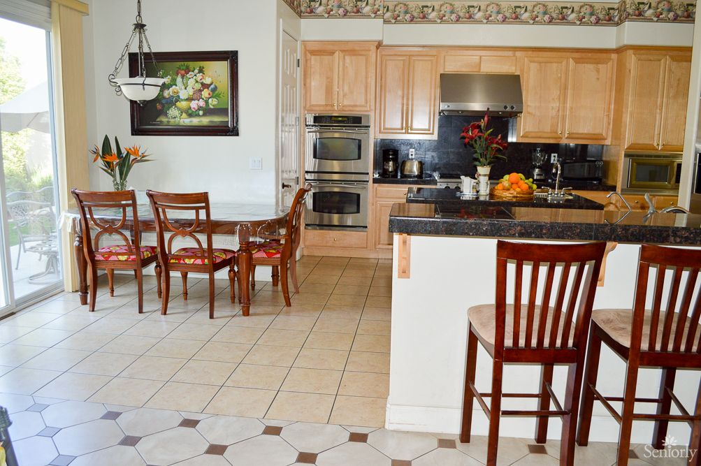 A modern kitchen and dining area featuring wooden cabinets, stainless steel appliances, and a stylish dining table with chairs.