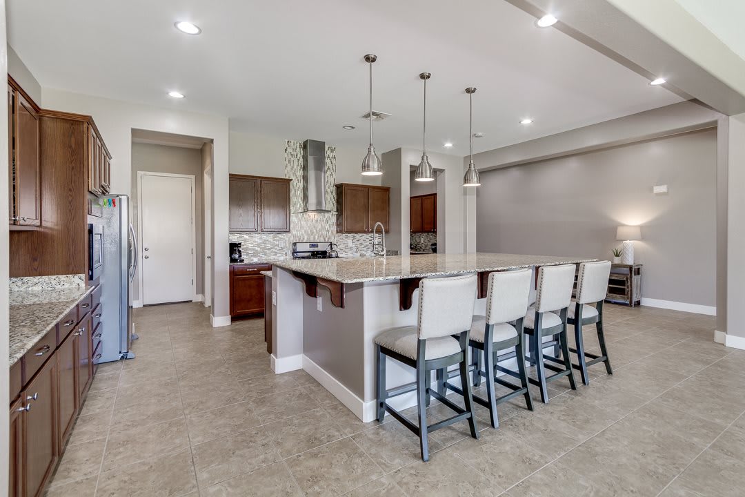 A modern kitchen featuring an island with bar stools and pendant lighting, complemented by stainless steel appliances.