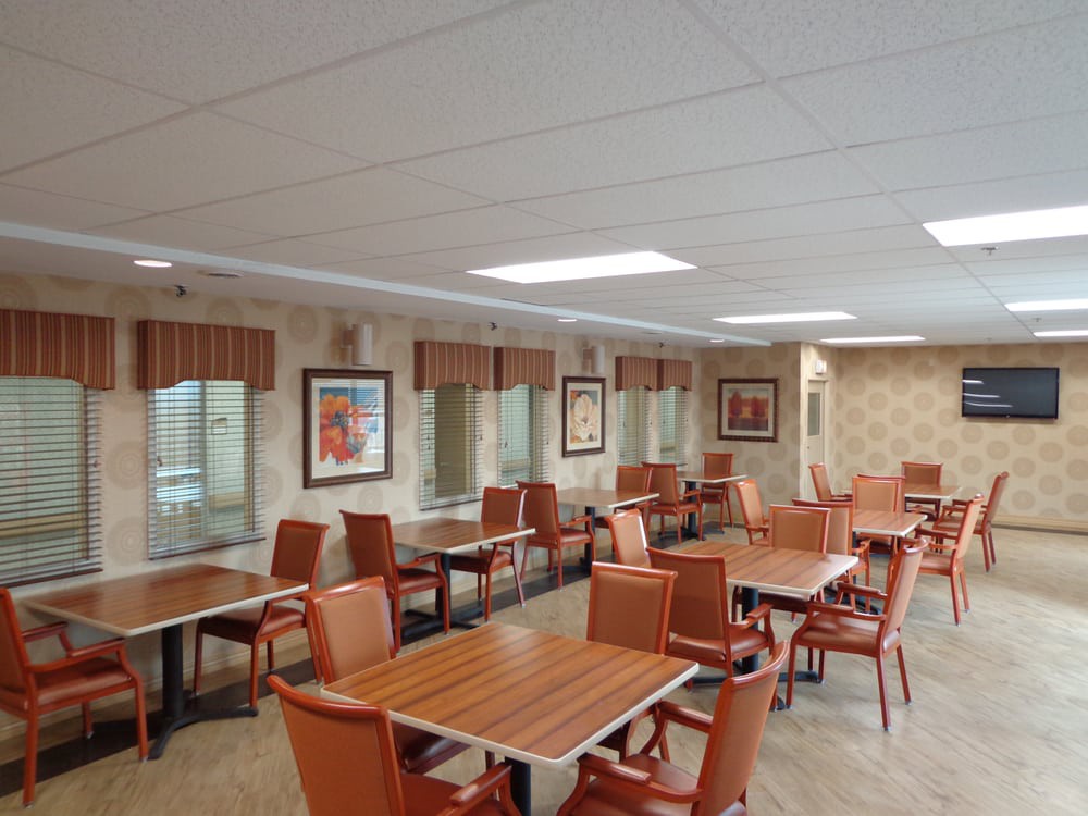 A well-lit dining area with multiple tables and chairs, decorated with framed artwork on the walls.