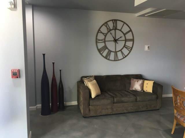 A modern living room featuring a comfortable sofa, decorative vases, and a large wall clock.