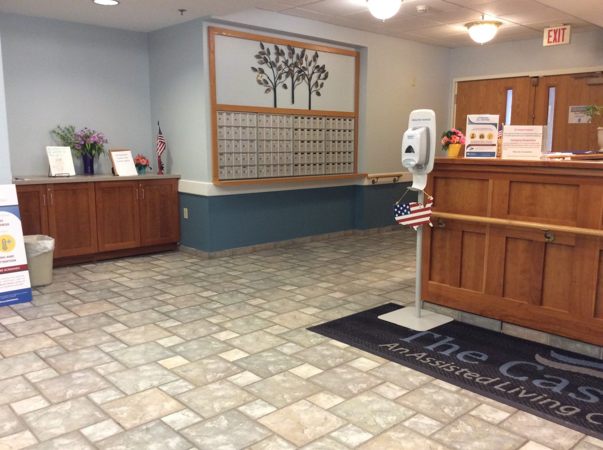 A tidy lobby or reception area with a decorative tree wall hanging and tile flooring.