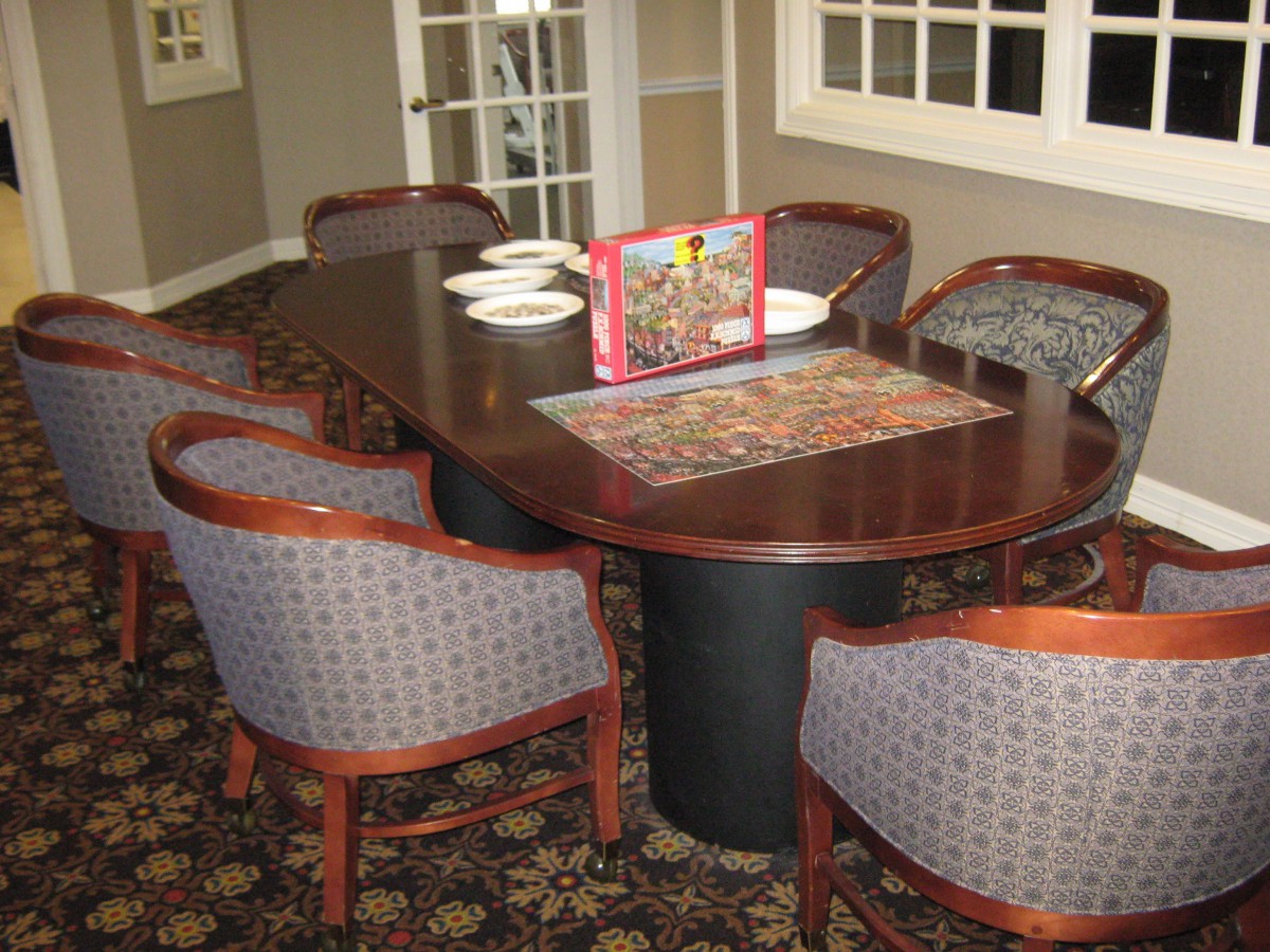 A dining table with chairs arranged around it, featuring a board game set up in the center.